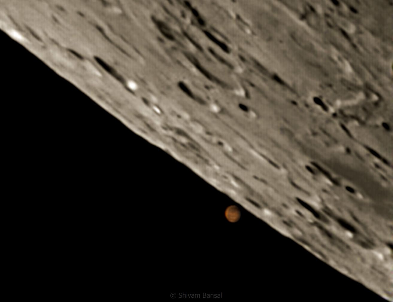 Tight telescopic shot of the Moon's cratered terminator edge with the reddish-orange disc of Mars visible separately below it in black sky.