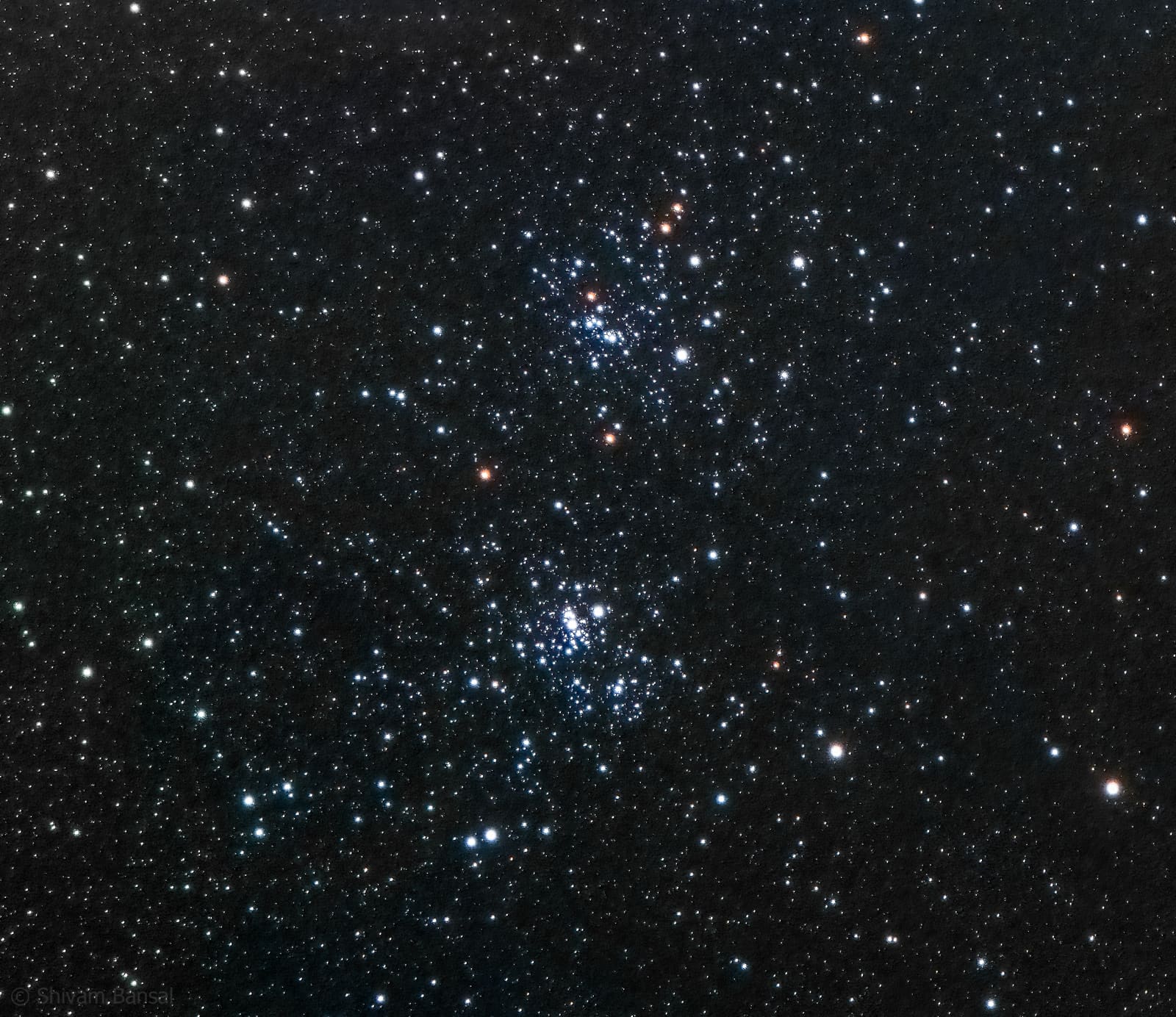 Two adjacent tight clusters of bright stars surrounded by a dense field of smaller background stars.