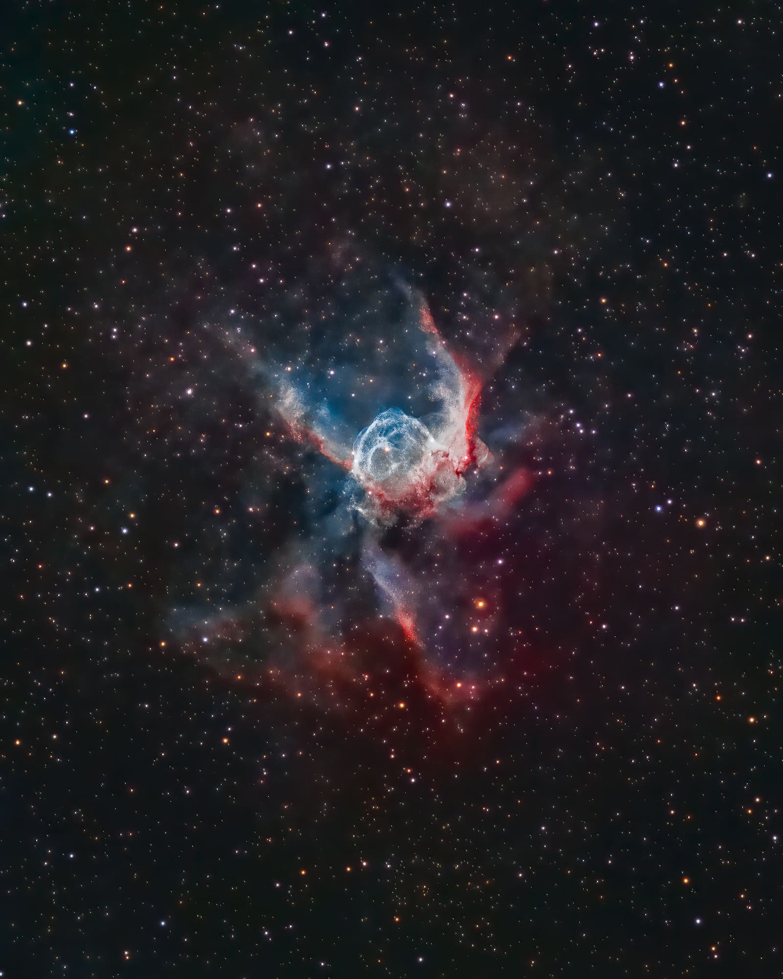 A nebula with a rounded blue-white central shell and red wing-shaped extensions on either side, set against a starfield.