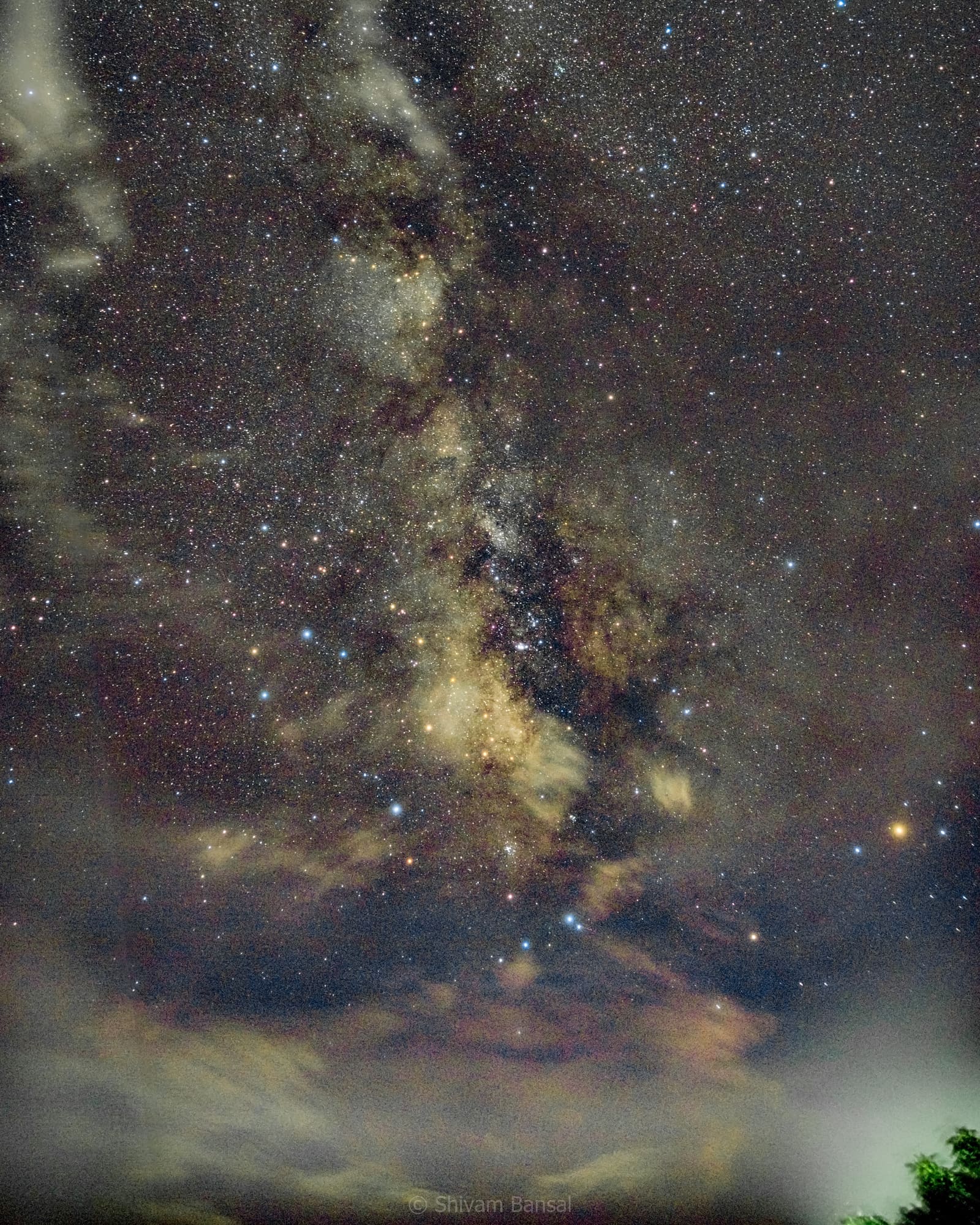 The Milky Way rising above a layer of warmly lit low clouds at Bera, Rajasthan.