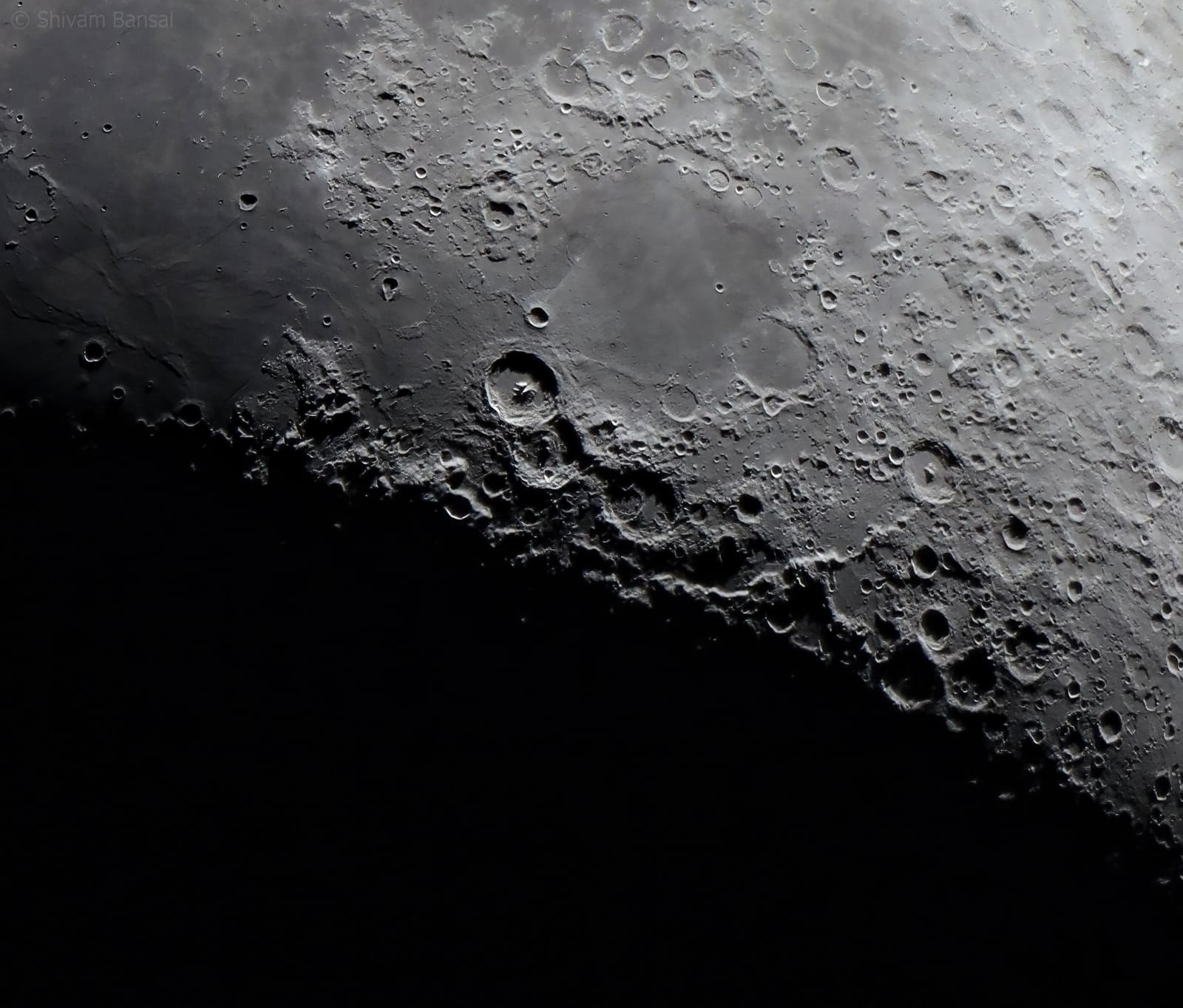 A close view along the Moon's terminator line, with craters and ridges thrown into sharp shadow relief.