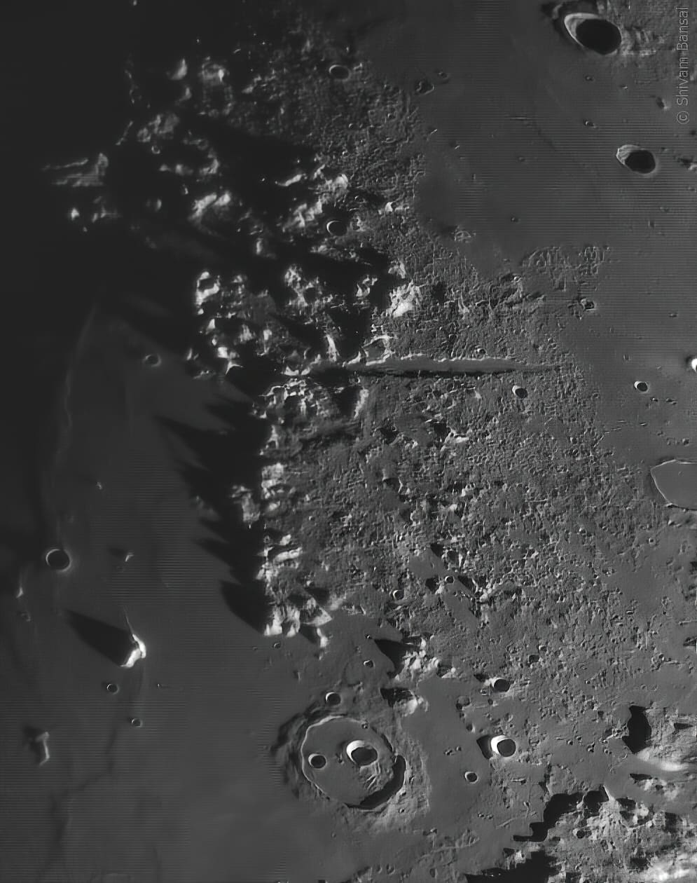 A mountain range on the Moon with a long straight valley cutting through it, photographed near the terminator.