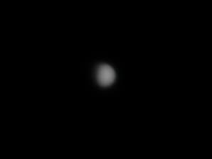 Small, soft-focus telescopic image of Mercury as a pale grey circular disc against a dark background.